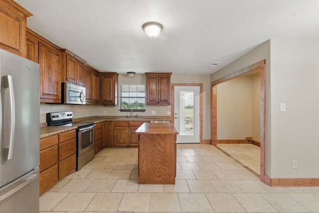 2790 Fairview Rd, Millsap, TX 76066 - kitchen with appliances with stainless steel finishes, a sink, brown cabinets, baseboards, and a kitchen island