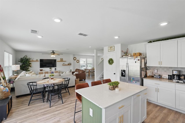 1943 Applewood Trl, Forney, TX 75126 - kitchen featuring stainless steel refrigerator with ice dispenser, ceiling fan, white cabinets, a kitchen breakfast bar, and light countertops