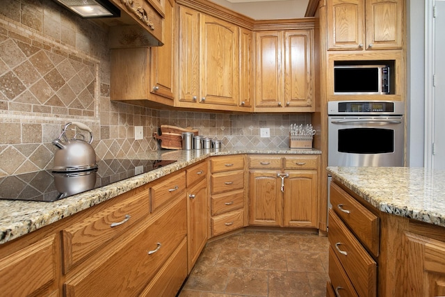 4816 Prairie Chapel Trl, Crandall, TX 75114 - kitchen featuring stainless steel appliances, decorative backsplash, light stone counters, dark stone finish floors, and brown cabinetry