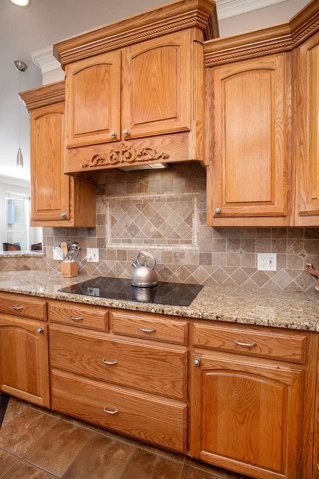 4816 Prairie Chapel Trl, Crandall, TX 75114 - kitchen with black electric cooktop, backsplash, light stone counters, crown molding, and brown cabinetry