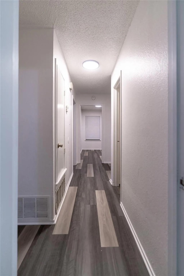 1030 Tyler St, Cooper, TX 75432 - hallway featuring dark wood-style flooring, a textured ceiling, and baseboards
