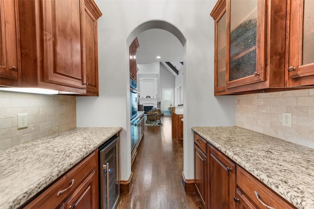 5061 Copperglen Cir, Colleyville, TX 76034 - kitchen featuring beverage cooler, decorative backsplash, dark wood-style flooring, glass insert cabinets, and light stone countertops