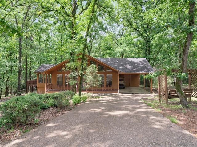 136 Lariat Loop, Holly Lake Ranch, TX 75765 - rustic home with driveway, a shingled roof, a carport, and a view of trees