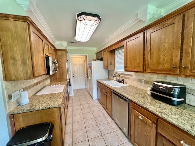 3377 W Moonlight Dr, Robinson, TX 76706 - kitchen featuring stainless steel appliances, a sink, brown cabinetry, ornamental molding, and decorative backsplash