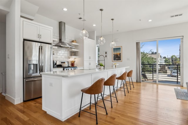 5023 Fuqua St Unit 101, Dallas, TX 75206 - kitchen with stainless steel appliances, wall chimney exhaust hood, light wood-style flooring, recessed lighting, and backsplash