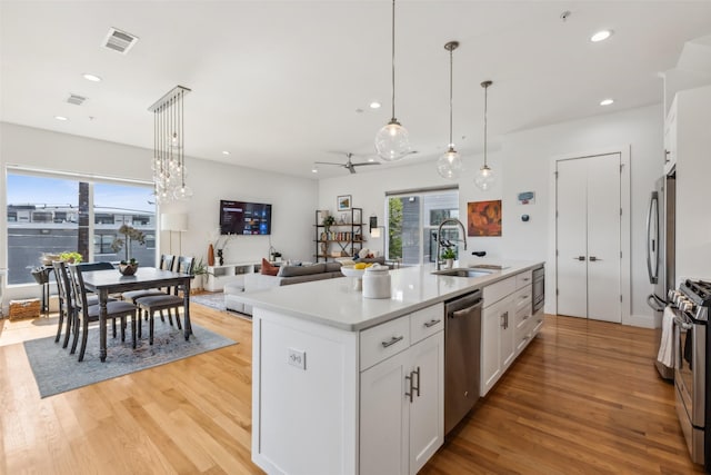 5023 Fuqua St Unit 101, Dallas, TX 75206 - kitchen featuring appliances with stainless steel finishes, a sink, light wood finished floors, white cabinetry, and plenty of natural light
