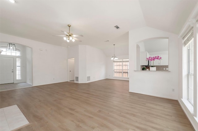 3072 Bigleaf Dr, Little Elm, TX 75068 - unfurnished living room with arched walkways, vaulted ceiling, a ceiling fan, light wood-type flooring, and a chandelier