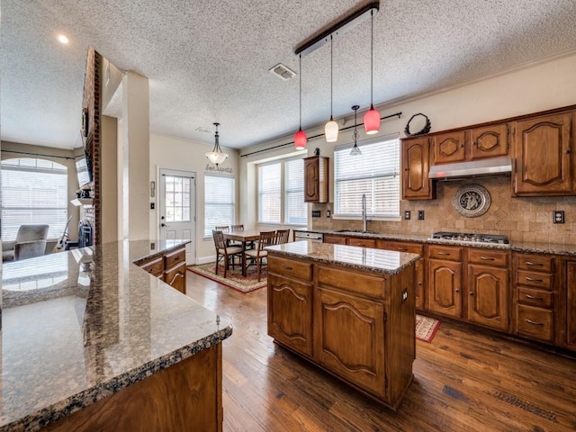 3968 Valez Dr, Carrollton, TX 75007 - kitchen featuring a sink, a center island, under cabinet range hood, dark wood-type flooring, and a textured ceiling