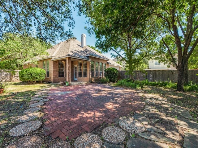 2614 Tourette Ct, Mckinney, TX 75070 - rear view of house featuring brick siding, a fenced backyard, and a chimney