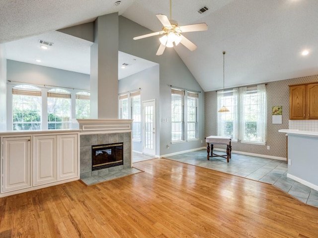 2614 Tourette Ct, Mckinney, TX 75070 - unfurnished living room with baseboards, a fireplace, light wood finished floors, a ceiling fan, and high vaulted ceiling