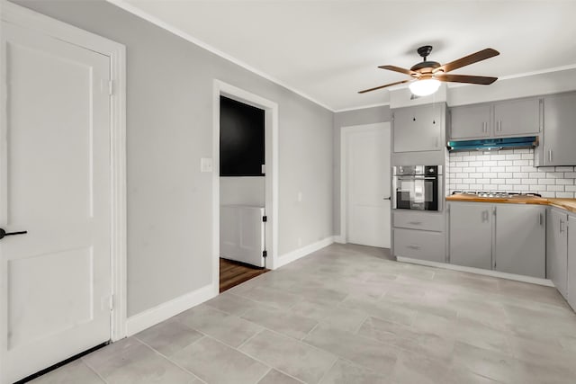 1316 Elm St, Bonham, TX 75418 - kitchen with stainless steel appliances, gray cabinetry, under cabinet range hood, ceiling fan, and crown molding