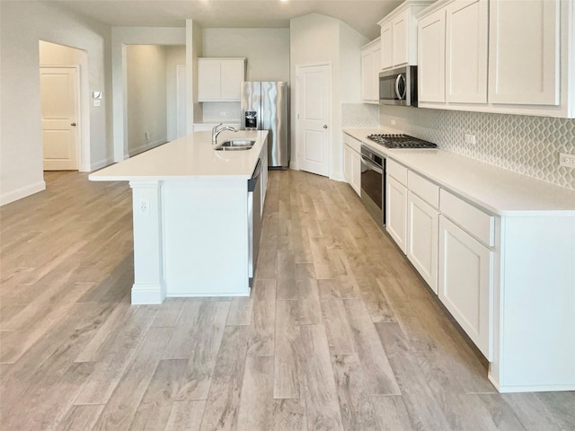 629 Brody Trl, Aledo, TX 76008 - kitchen featuring appliances with stainless steel finishes, a kitchen island with sink, tasteful backsplash, light countertops, and white cabinetry