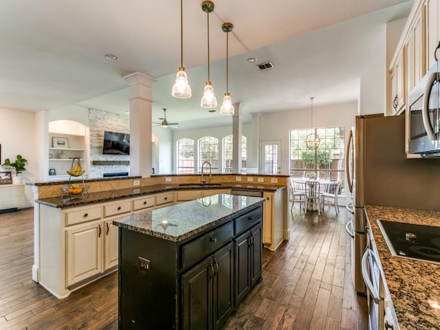 2270 Magic Mantle Dr, Lewisville, TX 75056 - kitchen with a spacious island, decorative columns, dark wood-style flooring, open floor plan, and stainless steel microwave