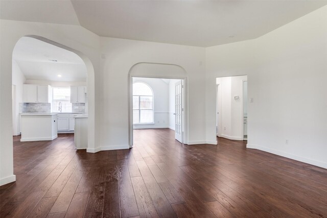 7405 Armstrong Ln, Rowlett, TX 75089 - unfurnished living room with dark wood finished floors, arched walkways, and baseboards