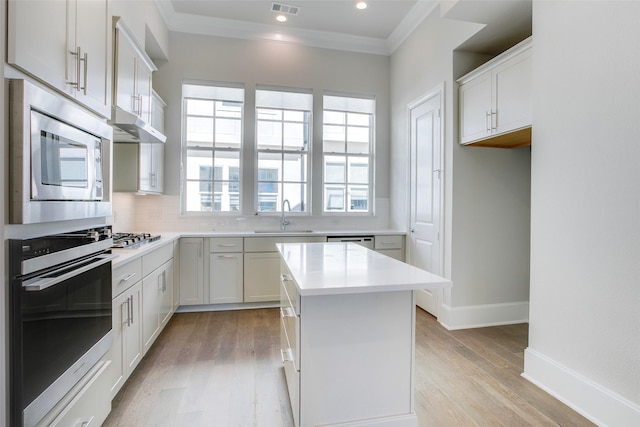 4651 New Water Ln, Dallas, TX 75219 - kitchen with stainless steel appliances, a sink, backsplash, crown molding, and light wood-type flooring