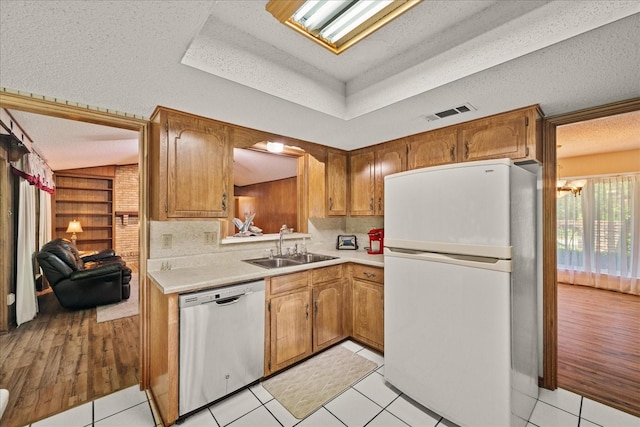 3601 University Dr, Garland, TX 75043 - kitchen with stainless steel dishwasher, freestanding refrigerator, a sink, light countertops, and a textured ceiling