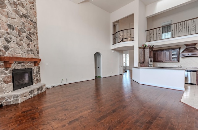 1101 Anchor Ter, Irving, TX 75063 - unfurnished living room with a high ceiling, a fireplace, wood finished floors, arched walkways, and baseboards