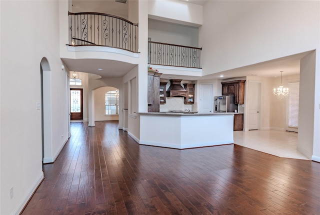 1101 Anchor Ter, Irving, TX 75063 - unfurnished living room featuring arched walkways, dark wood-type flooring, a chandelier, a towering ceiling, and baseboards