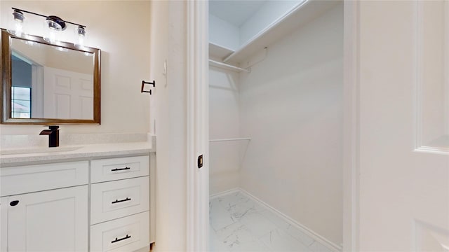 2605 Strother Dr, Garland, TX 75044 - bathroom with marble look tile flooring, vanity, a walk in closet, and baseboards