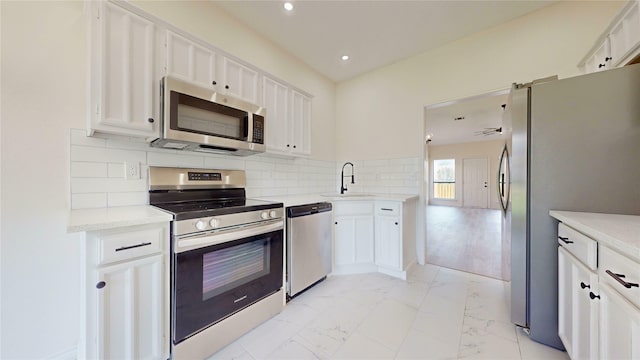 2605 Strother Dr, Garland, TX 75044 - kitchen featuring appliances with stainless steel finishes, a sink, light marble finish flooring, white cabinetry, and recessed lighting