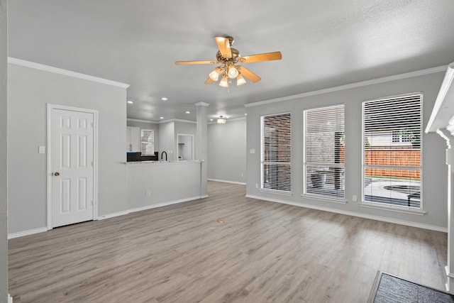 9117 Roundbluff Rd, Plano, TX 75025 - unfurnished living room featuring a ceiling fan, light wood-type flooring, baseboards, crown molding, and a sink
