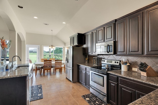 136 Devonshire Dr, Waxahachie, TX 75167 - kitchen featuring stainless steel appliances, a sink, arched walkways, vaulted ceiling, and decorative backsplash