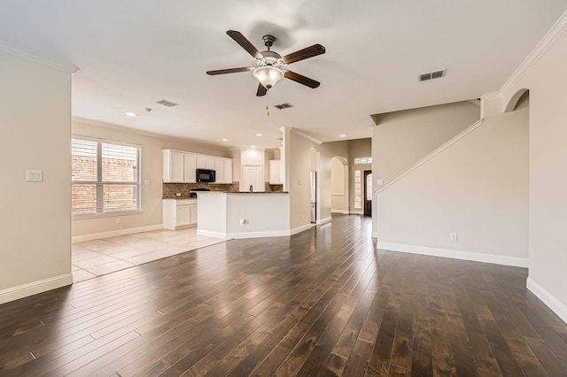 1017 Oarlock Dr, Crowley, TX 76036 - unfurnished living room with arched walkways, crown molding, a ceiling fan, dark wood finished floors, and baseboards