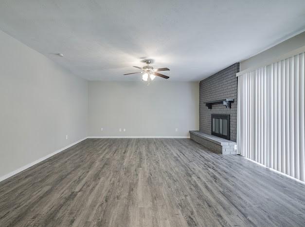1901 Castille Dr, Carrollton, TX 75007 - unfurnished living room with wood finished floors, ceiling fan, baseboards, and a fireplace
