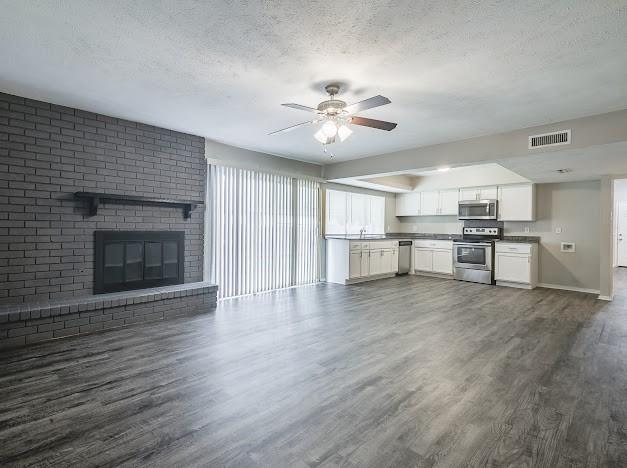 1901 Castille Dr, Carrollton, TX 75007 - unfurnished living room with a textured ceiling, dark wood-type flooring, ceiling fan, and healthy amount of natural light