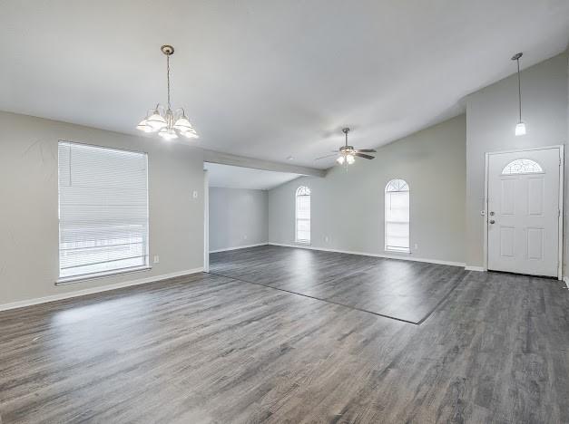 1901 Castille Dr, Carrollton, TX 75007 - unfurnished living room with vaulted ceiling, wood finished floors, baseboards, a chandelier, and ceiling fan