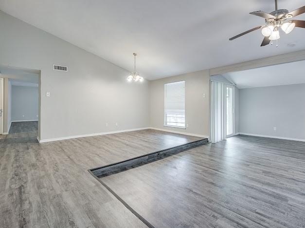 1901 Castille Dr, Carrollton, TX 75007 - empty room with lofted ceiling, wood finished floors, baseboards, a ceiling fan, and a chandelier