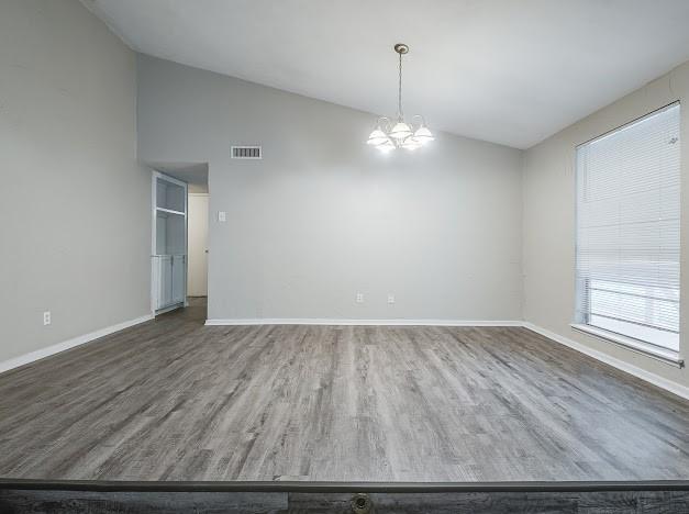 1901 Castille Dr, Carrollton, TX 75007 - unfurnished room featuring vaulted ceiling, wood finished floors, baseboards, and a chandelier