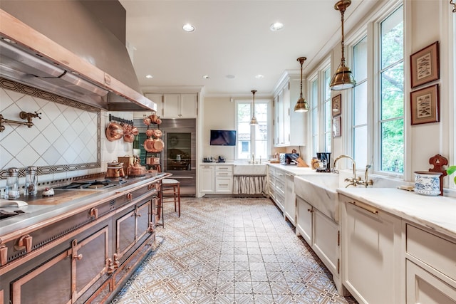 4107 Turtle Creek Blvd, Dallas, TX 75219 - kitchen with island exhaust hood, backsplash, a sink, pendant lighting, and stainless steel appliances