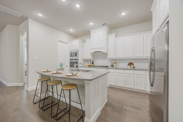 14844 Gentry Dr, Aledo, TX 76008 - kitchen with stainless steel appliances, a sink, wood finished floors, light countertops, and white cabinets