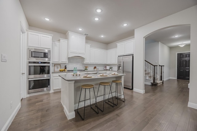 14844 Gentry Dr, Aledo, TX 76008 - kitchen with appliances with stainless steel finishes, arched walkways, dark wood-style flooring, white cabinets, and an island with sink
