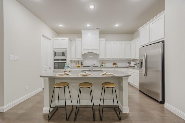 14844 Gentry Dr, Aledo, TX 76008 - kitchen featuring appliances with stainless steel finishes, a breakfast bar, white cabinetry, a kitchen island with sink, and recessed lighting