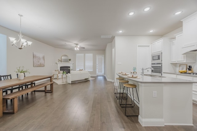 14844 Gentry Dr, Aledo, TX 76008 - kitchen with a sink, appliances with stainless steel finishes, a ceiling fan, a fireplace, and white cabinetry