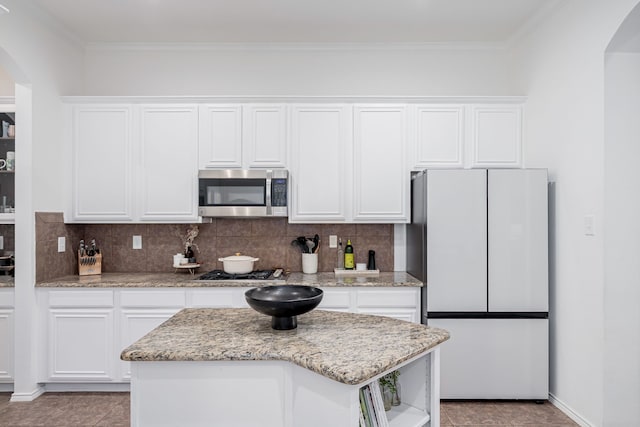 3159 Market Center Dr, Rockwall, TX 75032 - kitchen featuring stainless steel appliances, arched walkways, ornamental molding, white cabinets, and a center island