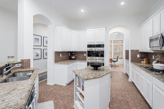 3159 Market Center Dr, Rockwall, TX 75032 - kitchen featuring a sink, stainless steel appliances, arched walkways, ornamental molding, and white cabinets
