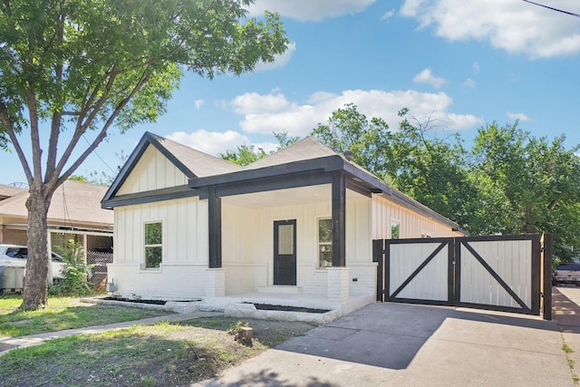 4612 Garland Ave, Dallas, TX 75223 - modern farmhouse style home with board and batten siding, brick siding, a gate, driveway, and covered porch
