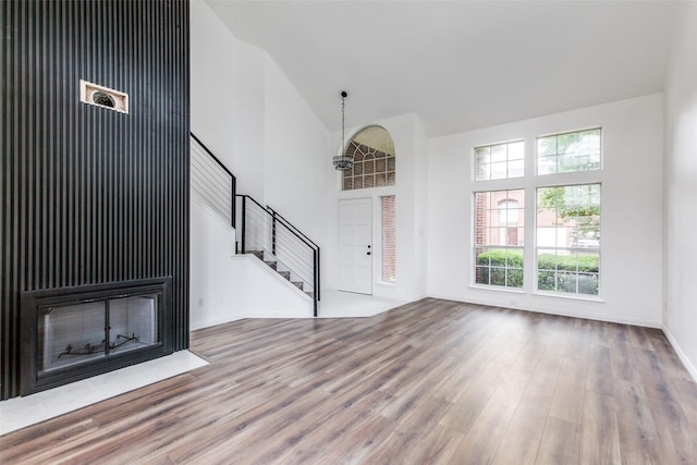 3713 Dentelle Dr, Plano, TX 75023 - unfurnished living room with high vaulted ceiling, wood finished floors, stairway, baseboards, and a fireplace with flush hearth