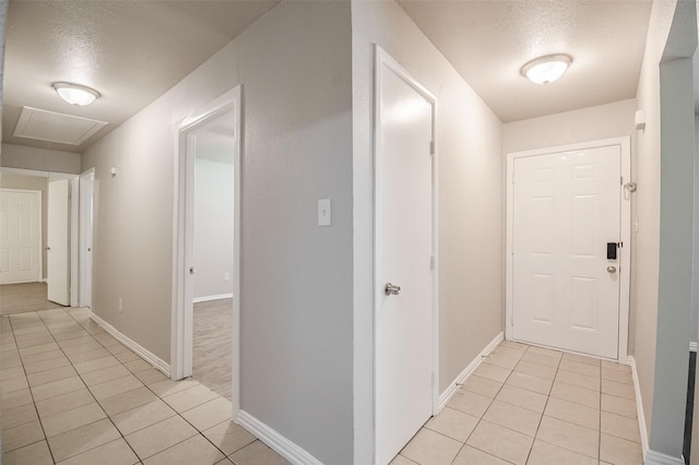 6917 Richlynn Ter, Richland Hills, TX 76118 - hall featuring attic access, light tile patterned floors, a textured ceiling, and baseboards