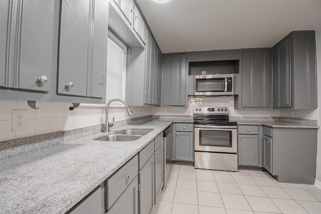 6917 Richlynn Ter, Richland Hills, TX 76118 - kitchen featuring appliances with stainless steel finishes, a sink, gray cabinetry, light tile patterned floors, and backsplash