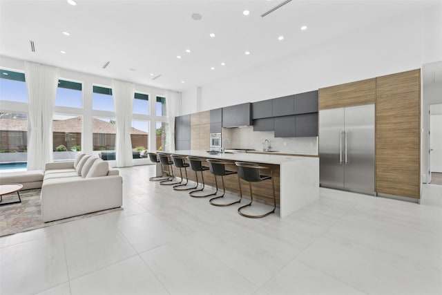11110 Saint Michaels Dr, Dallas, TX 75230 - kitchen with modern cabinets, a high ceiling, stainless steel built in fridge, light countertops, and a large island with sink