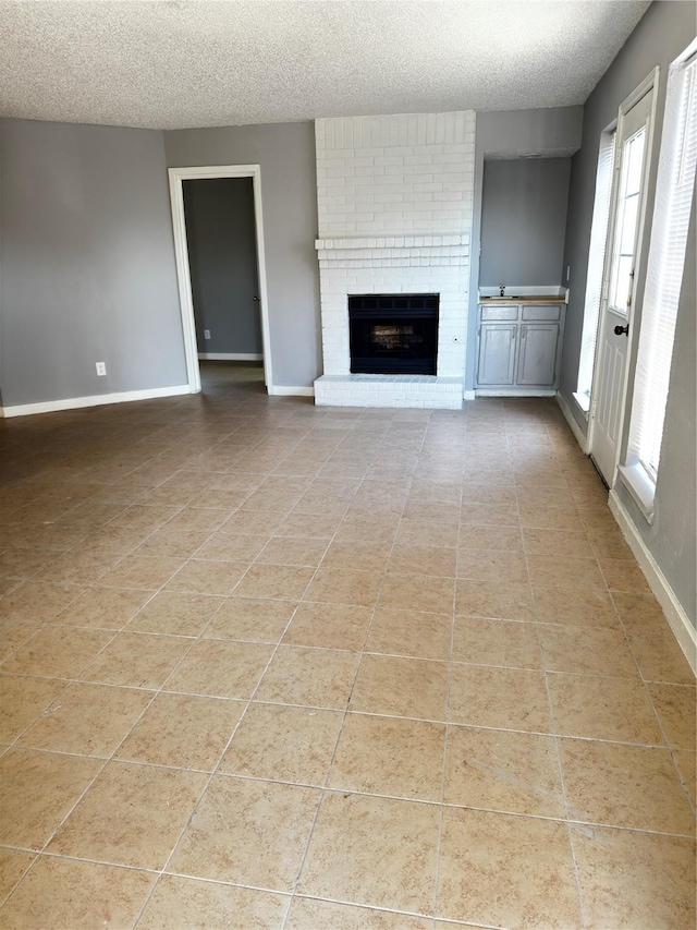 5412 Brookhollow Dr, Sachse, TX 75048 - unfurnished living room featuring a textured ceiling, baseboards, light tile patterned flooring, and a brick fireplace