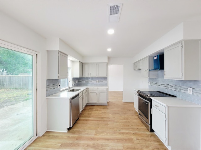 2317 Woodhollow Ave, Mesquite, TX 75150 - kitchen with stainless steel appliances, wall chimney exhaust hood, decorative backsplash, light wood-style floors, and recessed lighting