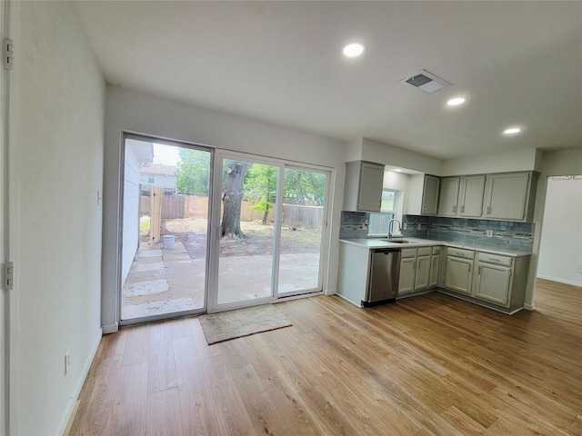 2317 Woodhollow Ave, Mesquite, TX 75150 - kitchen with light countertops, backsplash, light wood finished floors, stainless steel dishwasher, and a sink