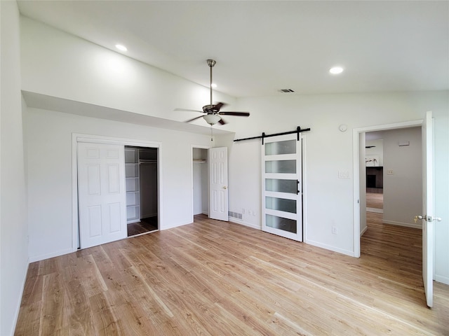 2317 Woodhollow Ave, Mesquite, TX 75150 - unfurnished bedroom with lofted ceiling, a barn door, light wood-style flooring, two closets, and baseboards