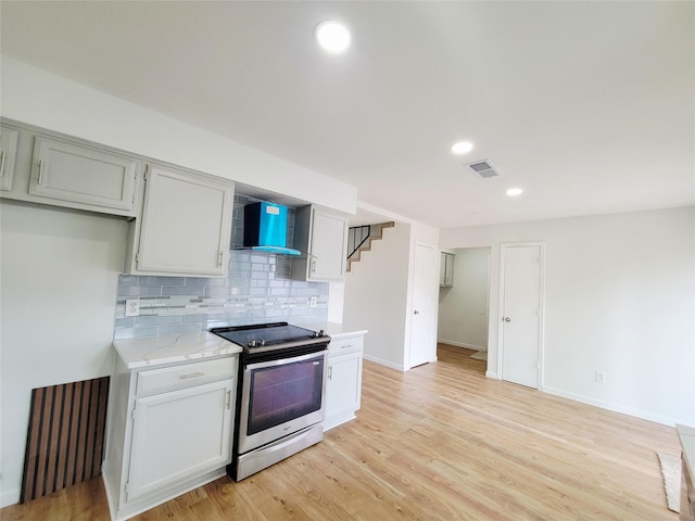 2317 Woodhollow Ave, Mesquite, TX 75150 - kitchen featuring stainless steel electric range oven, wall chimney range hood, tasteful backsplash, light wood-type flooring, and recessed lighting