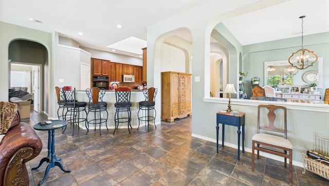 1409 Stoney Hills Dr, Cedar Hill, TX 75104 - kitchen with oven, a breakfast bar area, brown cabinets, a chandelier, and backsplash